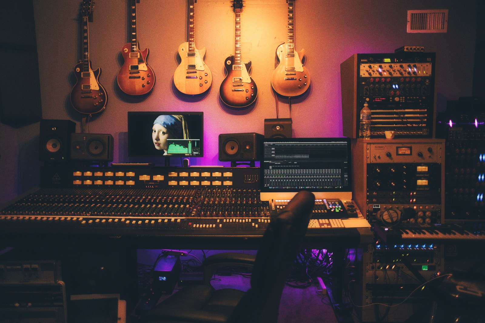 Recording studio with mixing console, monitors, keyboard and wall-mounted guitars